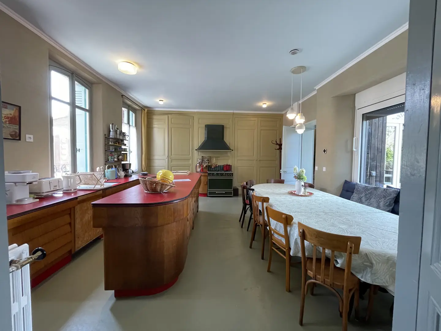 Grande cuisine conviviale avec longue table et îlot central rouge