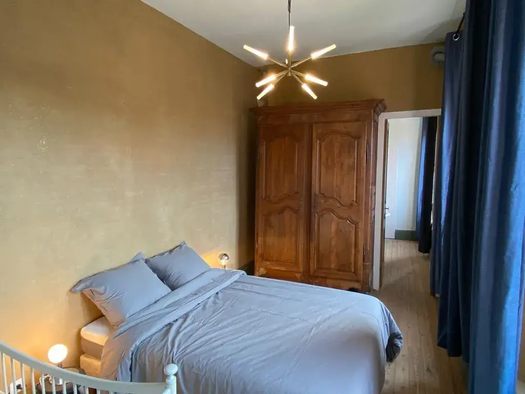 Chambre avec lit double, armoire ancienne, rideaux bleus et lit bébé