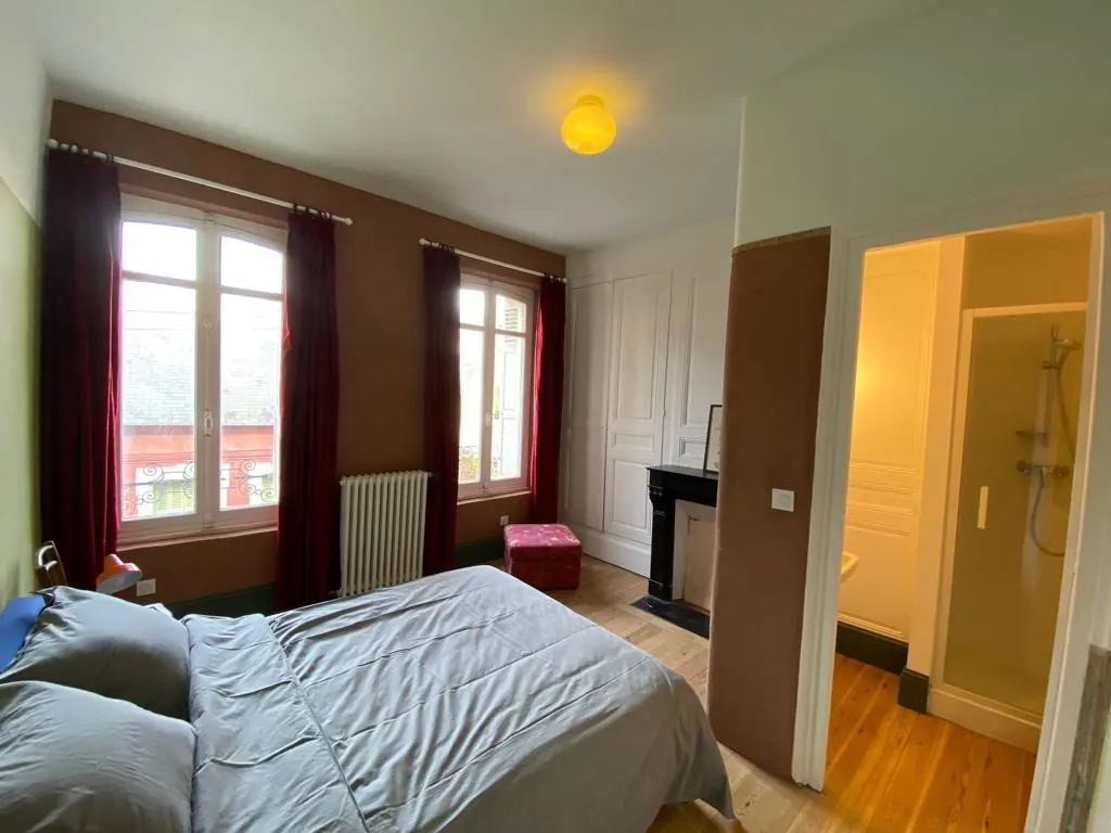 Chambre aux rideaux rouges avec lit double et salle de douche attenante
