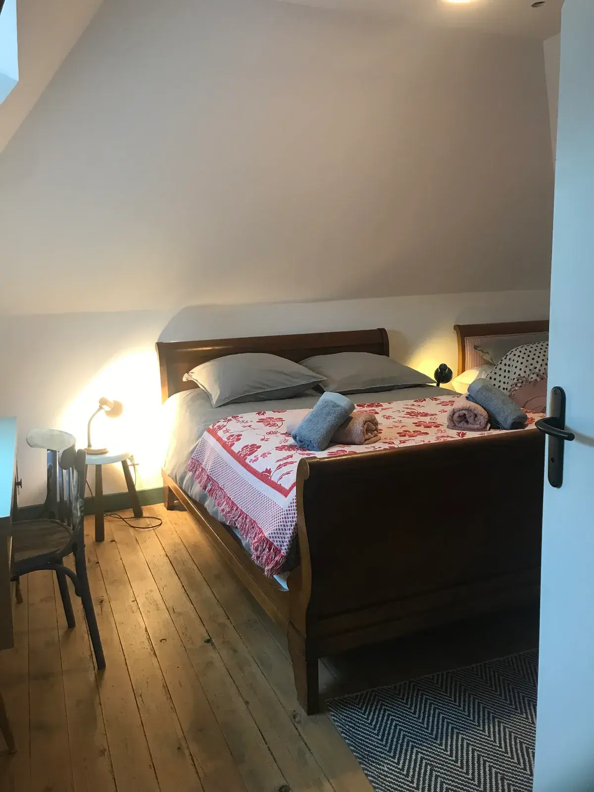 Chambre mansardée avec lit bateau ancien et parquet en bois brut