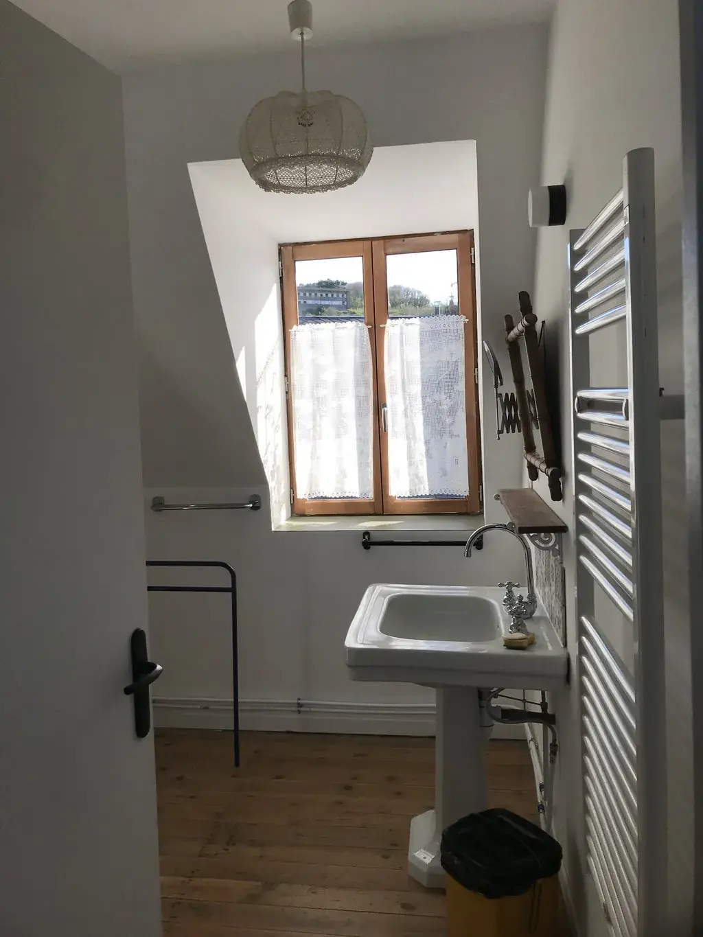 Salle de bain lumineuse du deuxième étage avec lavabo rétro et rideaux en dentelle