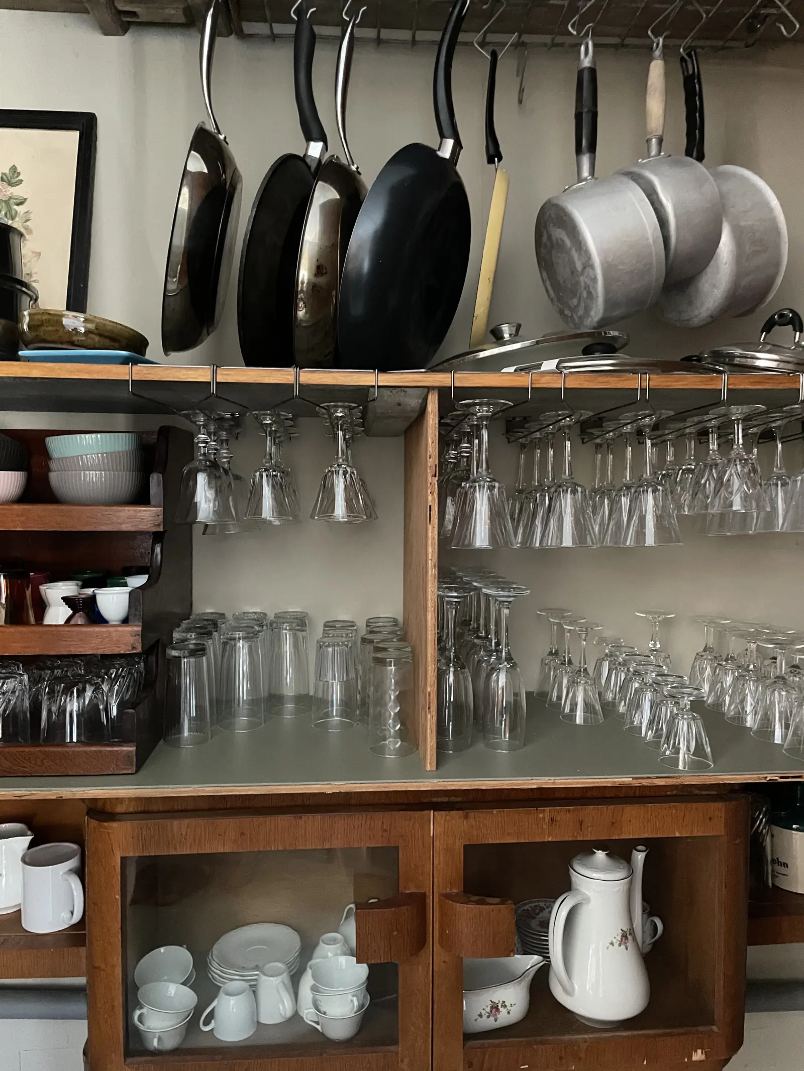 Vaisselier de la cuisine : verres alignés, casseroles suspendues et service ancien