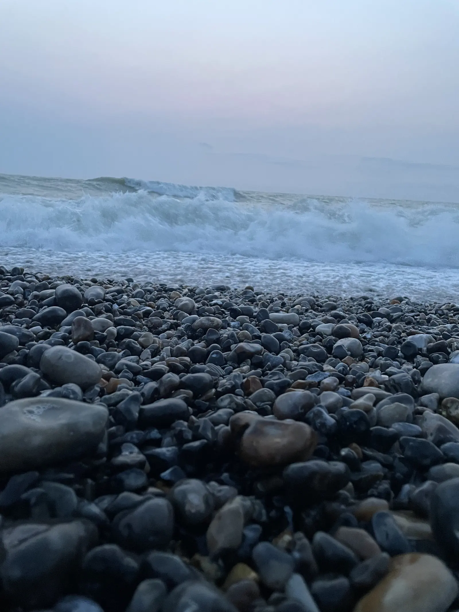 Une vague sur les galets de la plage, par temps couvert