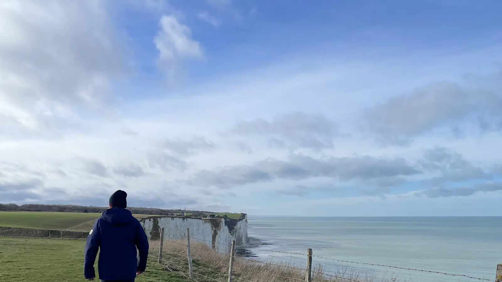 Un marcheur sur le sentier de crête au-dessus des falaises, sous un ciel bas